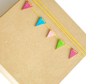 Simple gift box wrapped with bright colored yarn and embellished with wooden bunting.