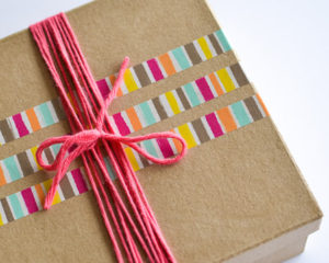 Gift wrapping: a simple gift box decorated with washi tape and brightly colored yarn.