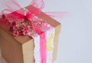 gift box wrapped with a strip of fabric, a tulle bow and artificial berries for embellishment