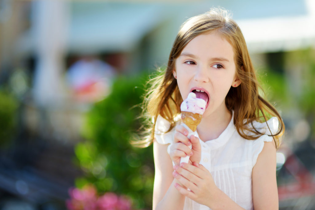 Adorable little girl eating tasty fresh ice cream outdoors