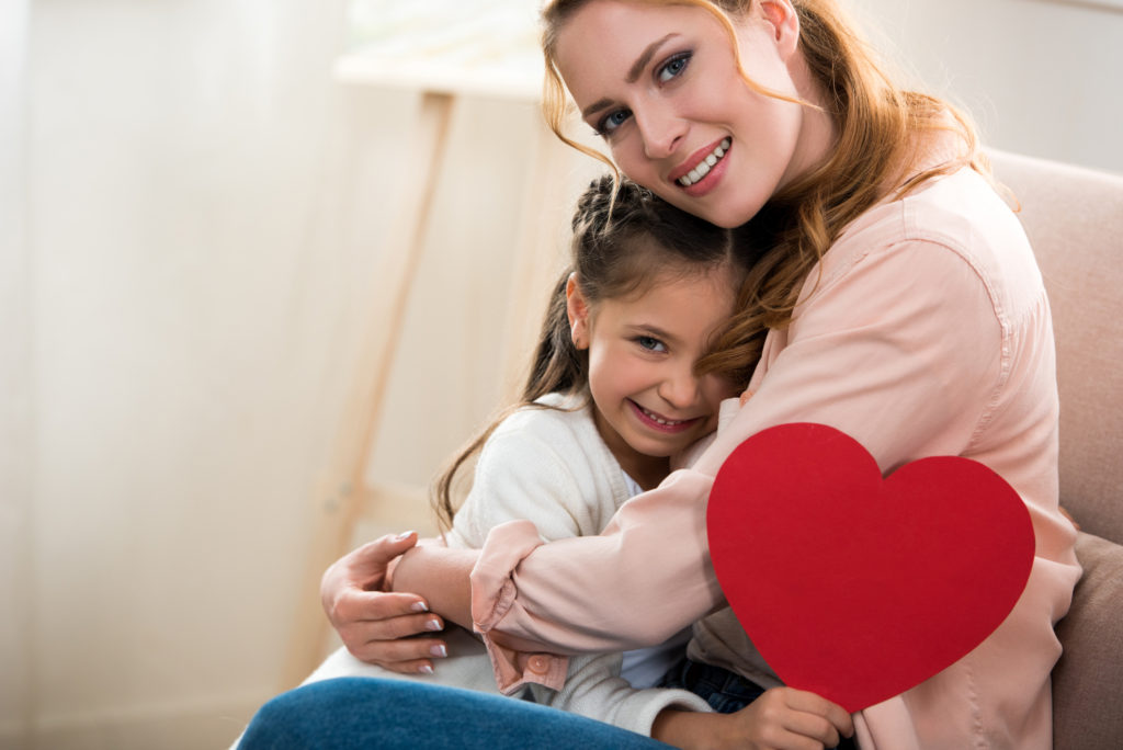 mother and daughter hugging holding a valentine.