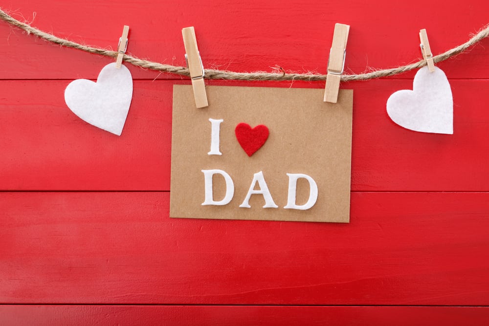 Fathers day message with felt hearts hanging with clothespins over red wooden board