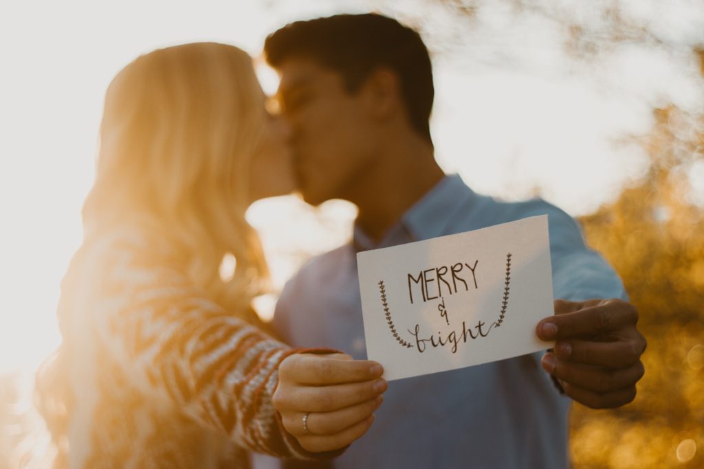 couple kissing, holding "merry & bright" card